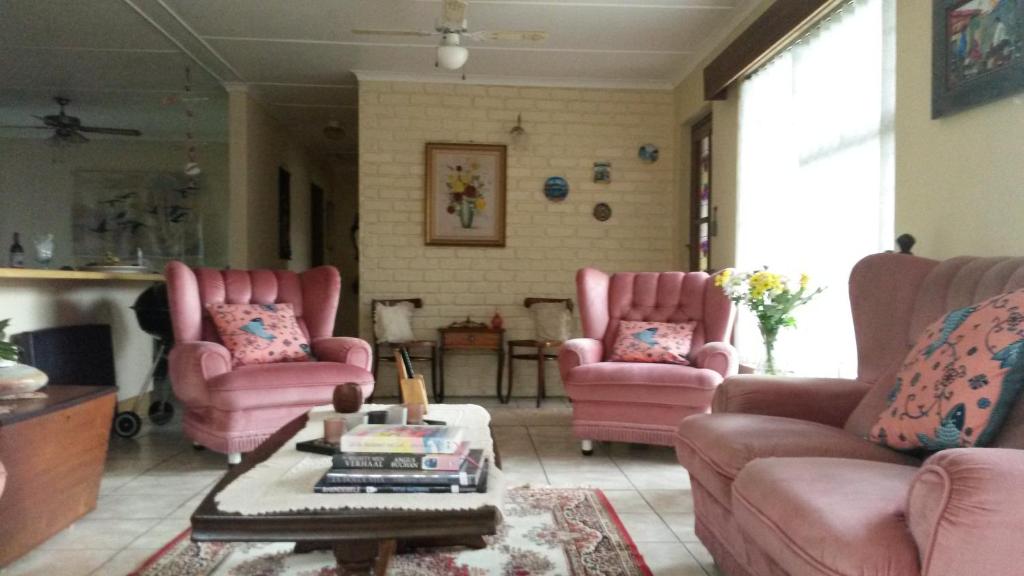 uma sala de estar com cadeiras cor-de-rosa e uma mesa em Beth-El em Mossel Bay