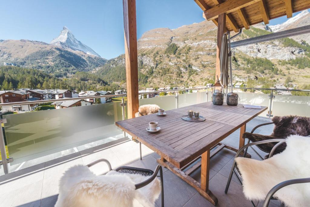 a table and chairs on a balcony with mountains at Apartment Alpharmonie in Zermatt