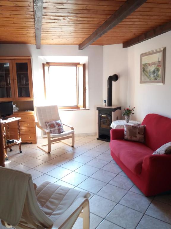 a living room with a red couch and a fireplace at Appartamento La Volpe in Pian degli Ontani