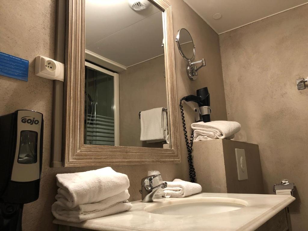 uma casa de banho com lavatório, espelho e toalhas em Best Western Hôtel De La Bourse em Mulhouse