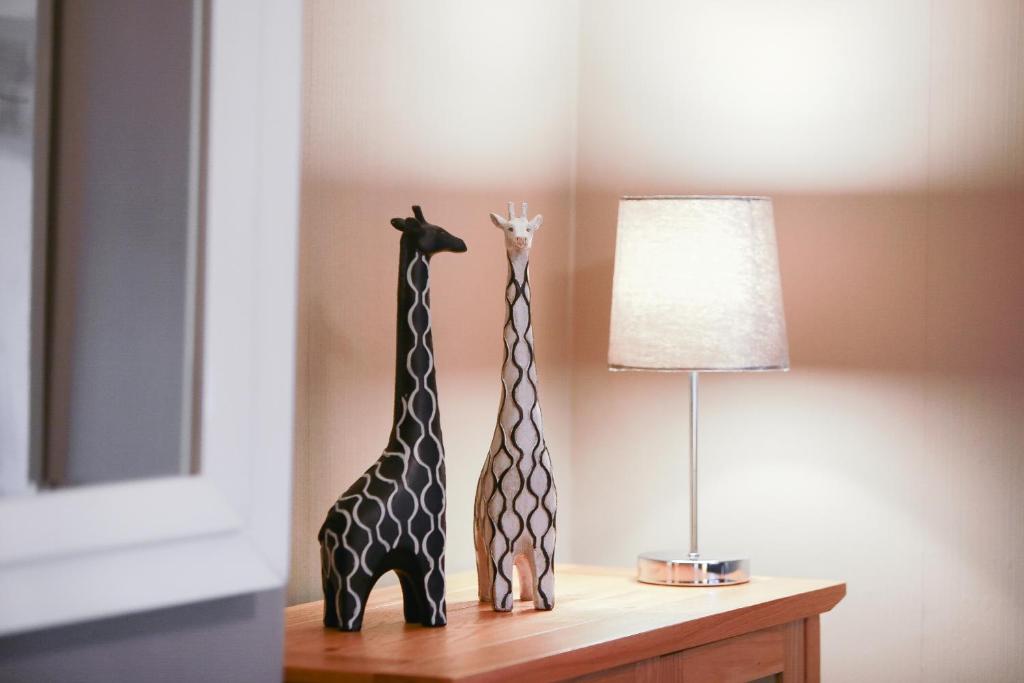 duas estátuas de girafa sentadas numa mesa ao lado de um candeeiro em Zoo House Chester em Chester