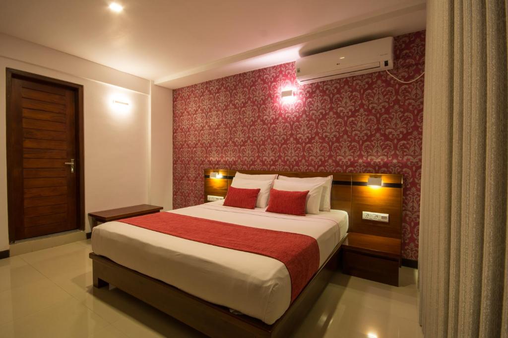 a bedroom with a large bed with a red wall at Ceyloni City Hotel in Kandy