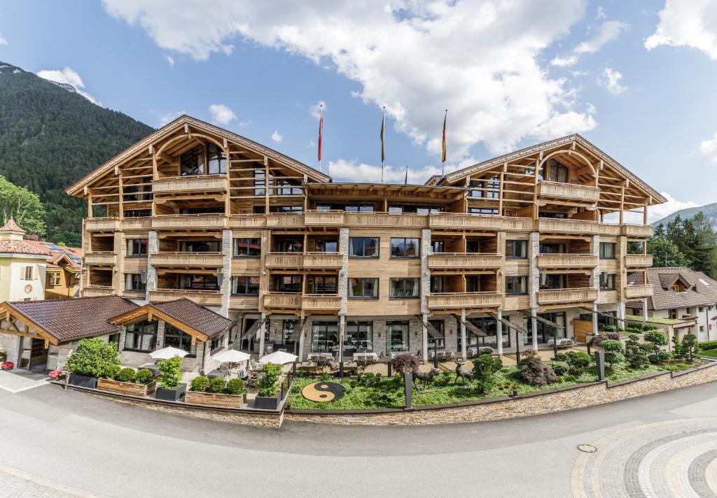 un grand bâtiment en bois sur le côté d'une route dans l'établissement Cocoon - Alpine Boutique Lodge, à Maurach