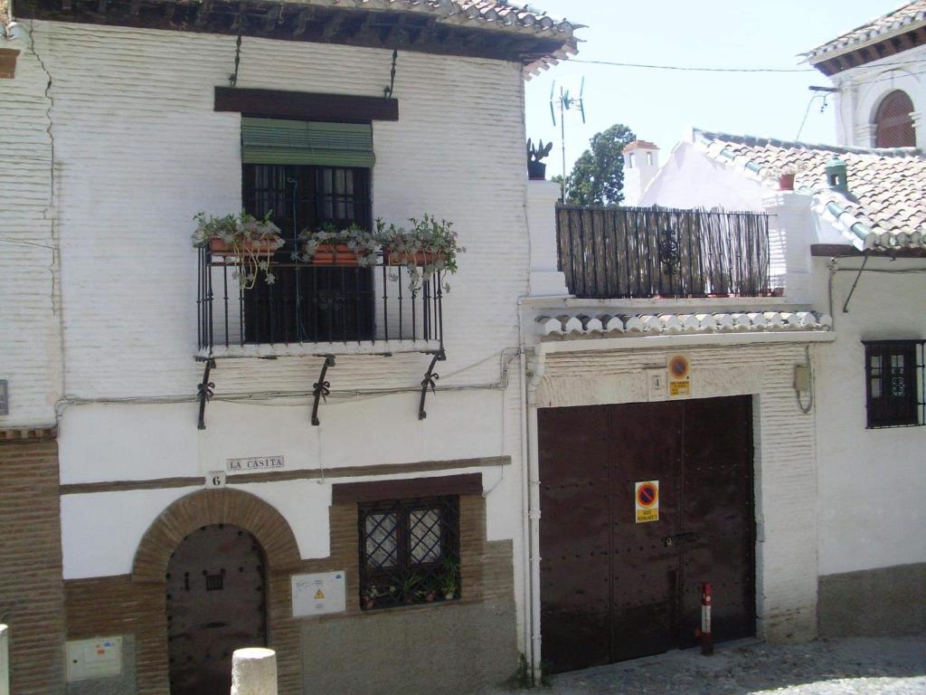 グラナダにあるLa Casita de Granadaの白い建物で、鉢植えの植物が植えられたバルコニーが付いています。