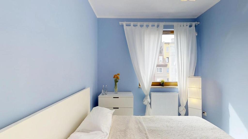 a blue bedroom with a bed and a window at Na Szancach 8E TectumApartments in Wrocław