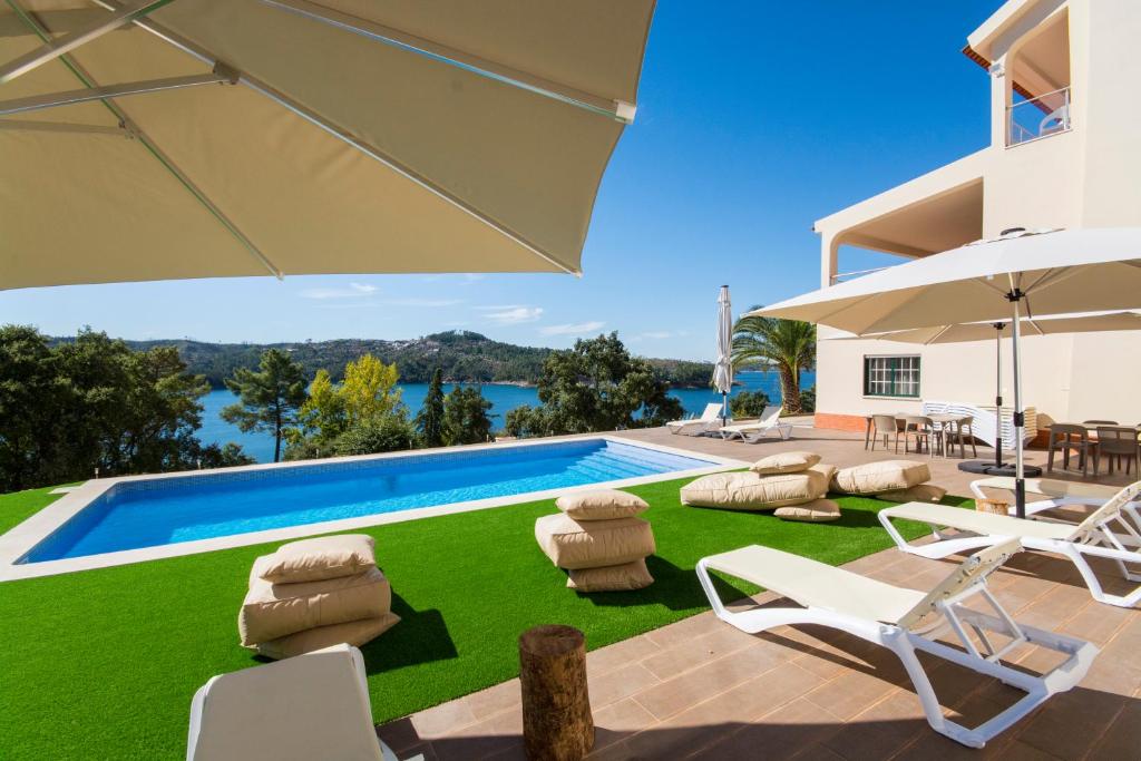 a villa with a swimming pool with chairs and an umbrella at Villa Nova Nautic & Nature in Eira do Chão