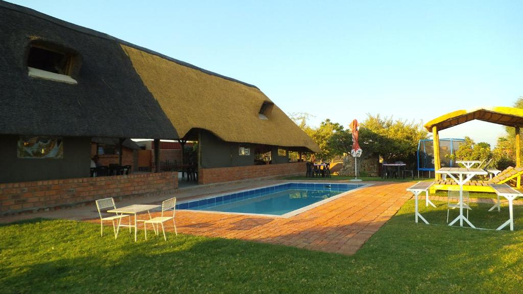 a pool with chairs and a table and a building at Pondoki Rest Camp in Groutfontein