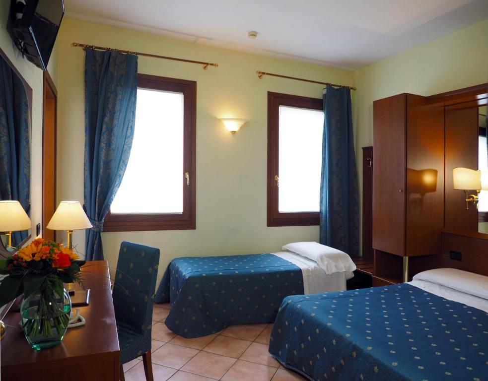 a hotel room with two beds and a table at Hotel Cris in Mestre