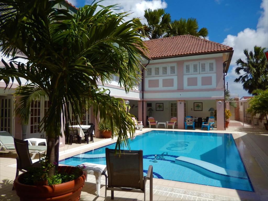 a pool in front of a house with a palm tree at Kamerlingh Villa in Oranjestad