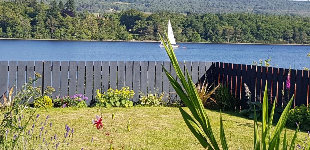 a yard with a fence and a body of water at Airanloch Bed & Breakfast, Loch Ness, Adult Only in Lochend