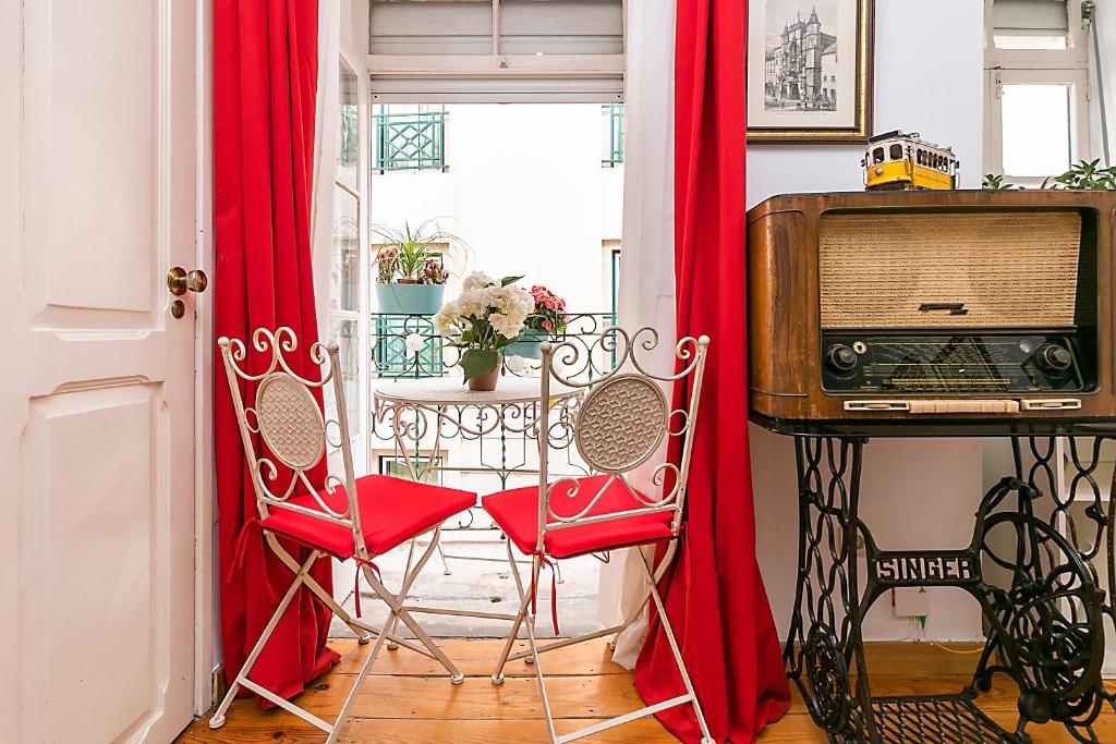 a room with two red chairs and a television at Romantic Apartment El Corte Inglês in Lisbon