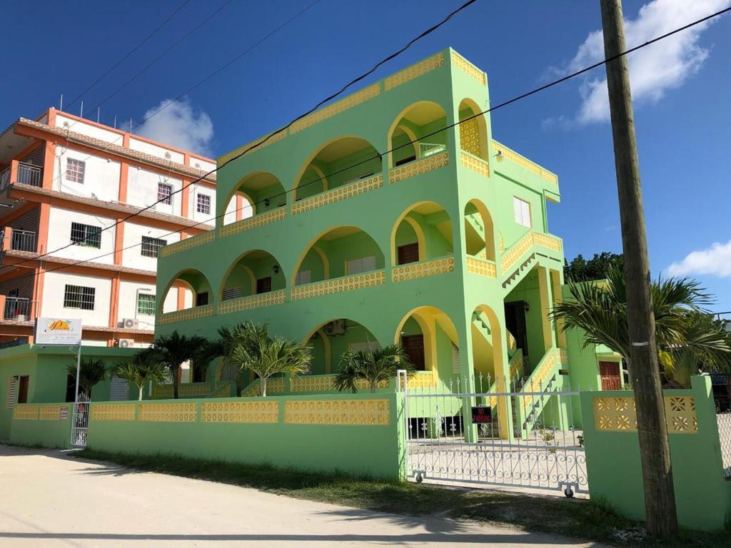 un bâtiment vert et jaune avec des palmiers devant lui dans l'établissement Panchos Villas, à Caye Caulker