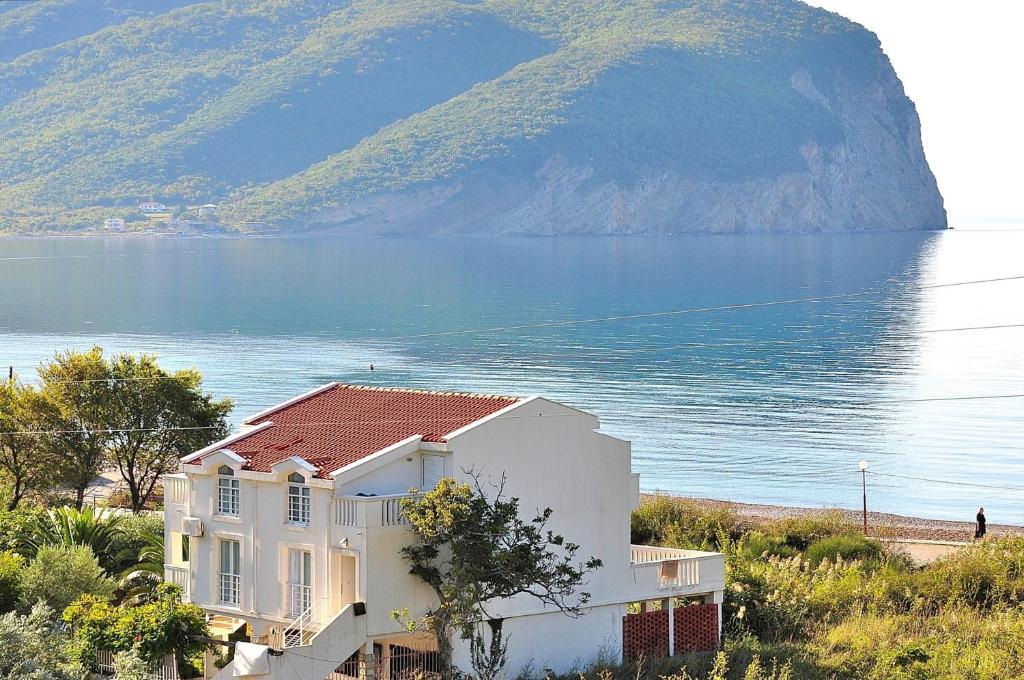 a house on a hill next to a body of water at Apartments Villa Marija in Petrovac na Moru