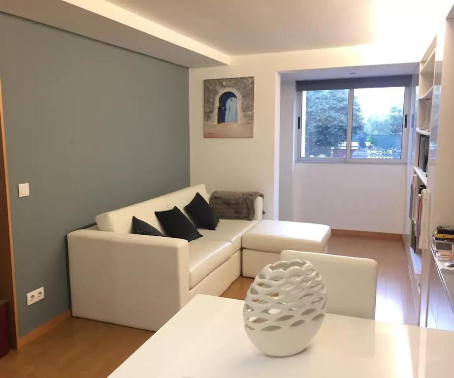 ein Wohnzimmer mit einem weißen Sofa und einem Tisch in der Unterkunft Maestro Appartment in Porto