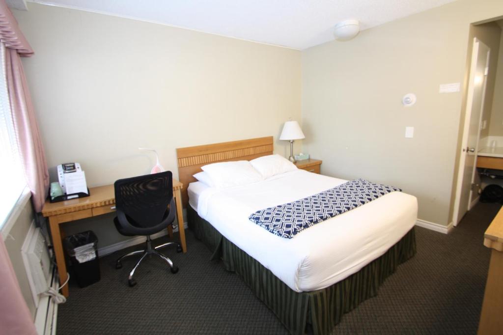 a bedroom with a bed and a desk and a chair at Harrison Spa Motel in Harrison Hot Springs