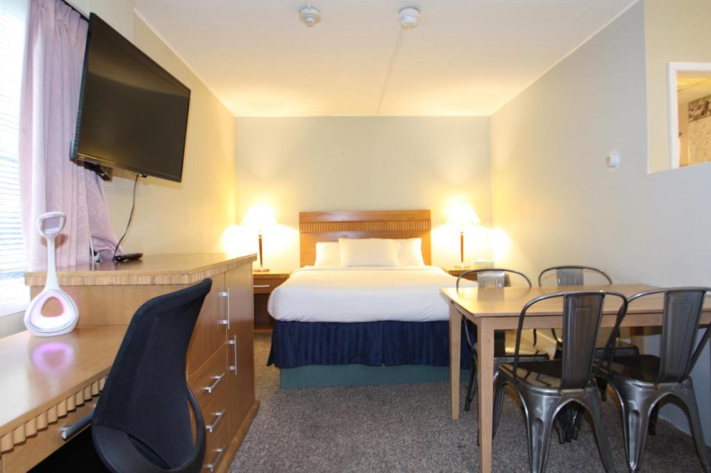 a hotel room with a bed and a table and chairs at Harrison Spa Motel in Harrison Hot Springs