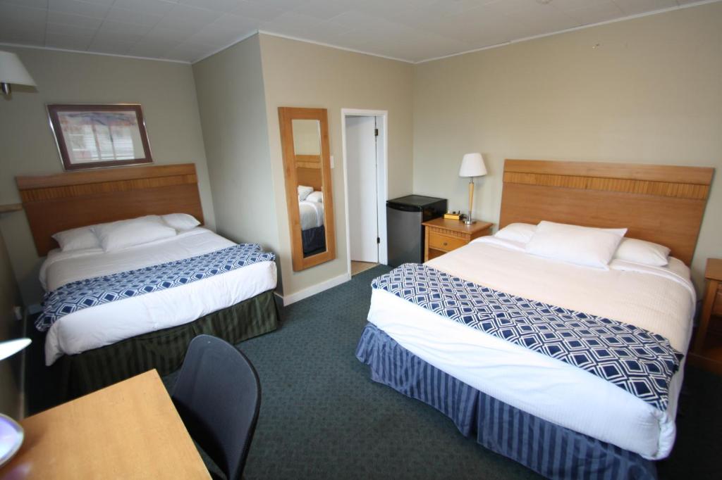 a hotel room with two beds and a table at Harrison Spa Motel in Harrison Hot Springs