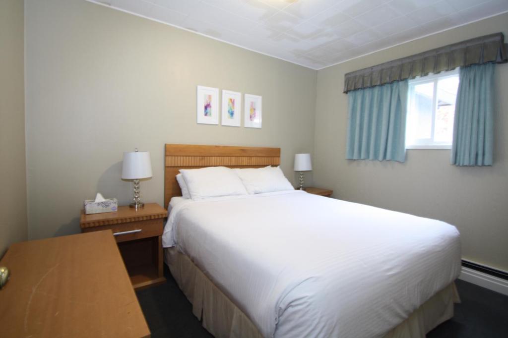 a bedroom with a large white bed and a window at Harrison Spa Motel in Harrison Hot Springs