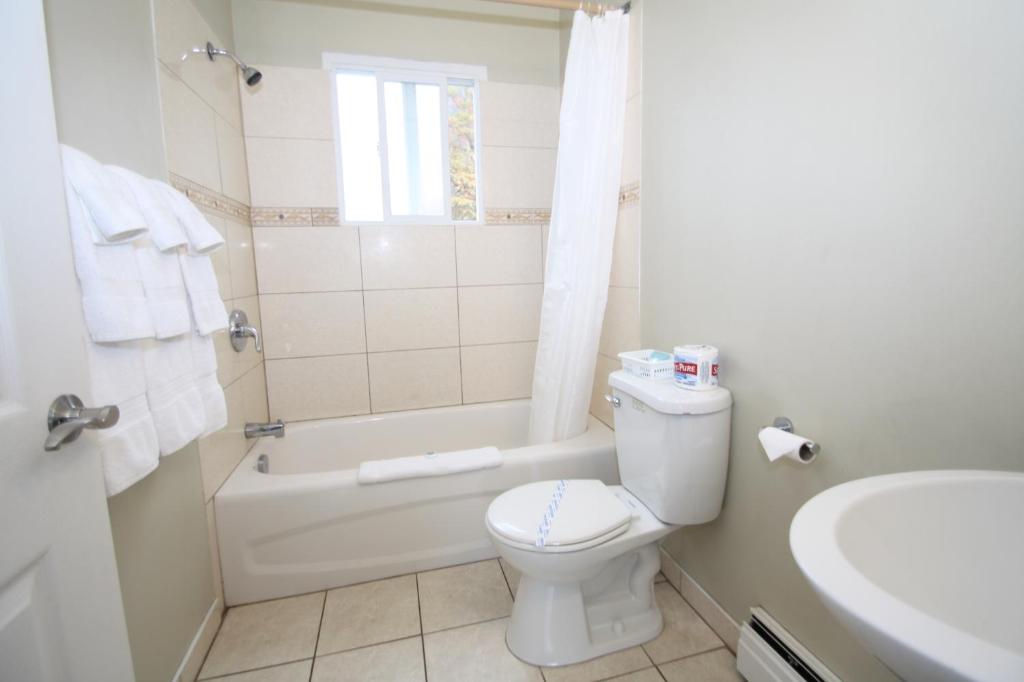 a bathroom with a toilet and a tub and a sink at Harrison Spa Motel in Harrison Hot Springs