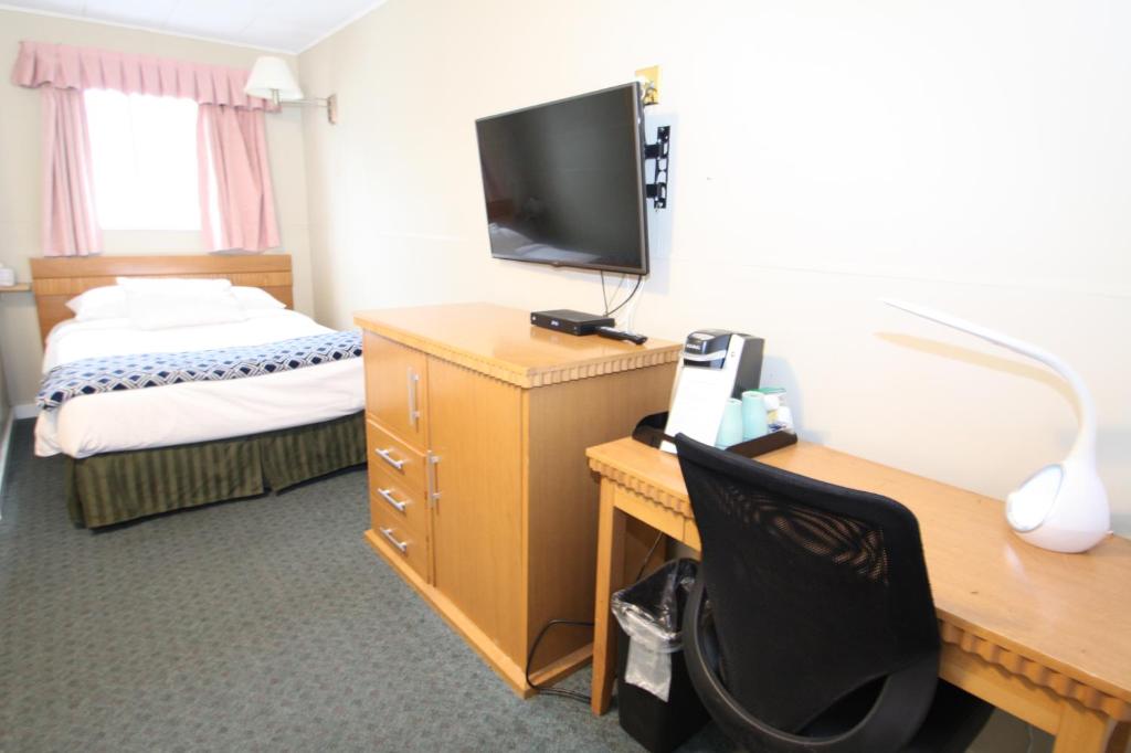 a hotel room with a desk and a television at Harrison Spa Motel in Harrison Hot Springs
