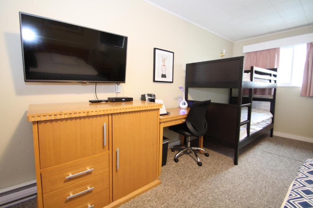 a bedroom with a desk with a computer and a television at Harrison Spa Motel in Harrison Hot Springs