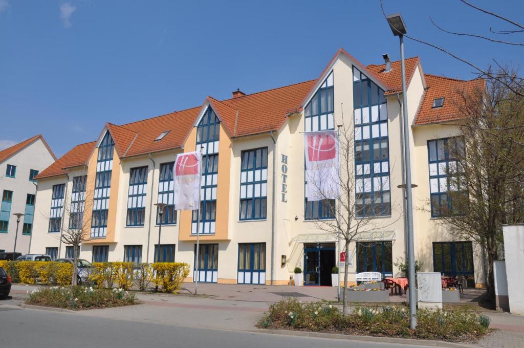 un grand bâtiment blanc avec un toit rouge dans l'établissement City Hotel Aschersleben, à Aschersleben