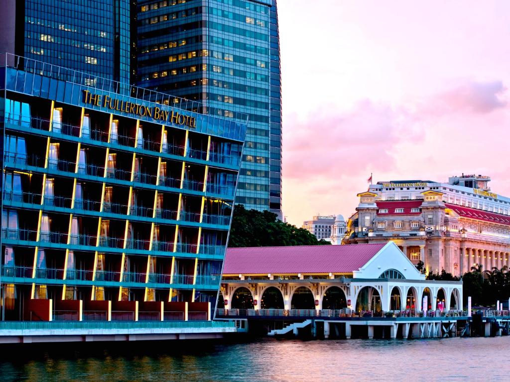 a hotel on the water next to some buildings at The Fullerton Bay Hotel Singapore in Singapore