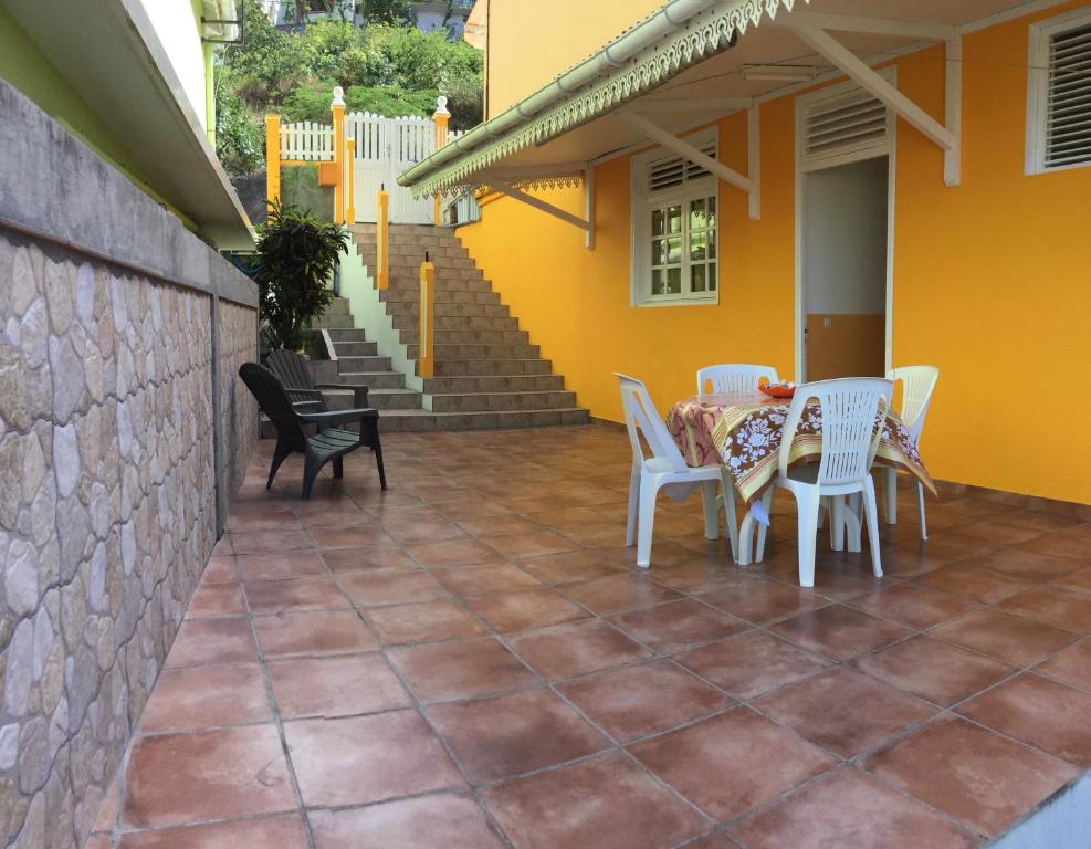 a patio with a table and chairs and a yellow house at Appt La Rose du Désert in Terre-de-Haut