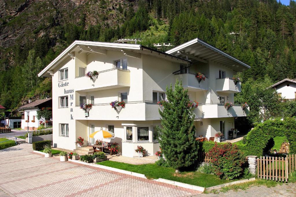 ein großes weißes Gebäude vor einem Berg in der Unterkunft Gästehaus Mrak in Längenfeld