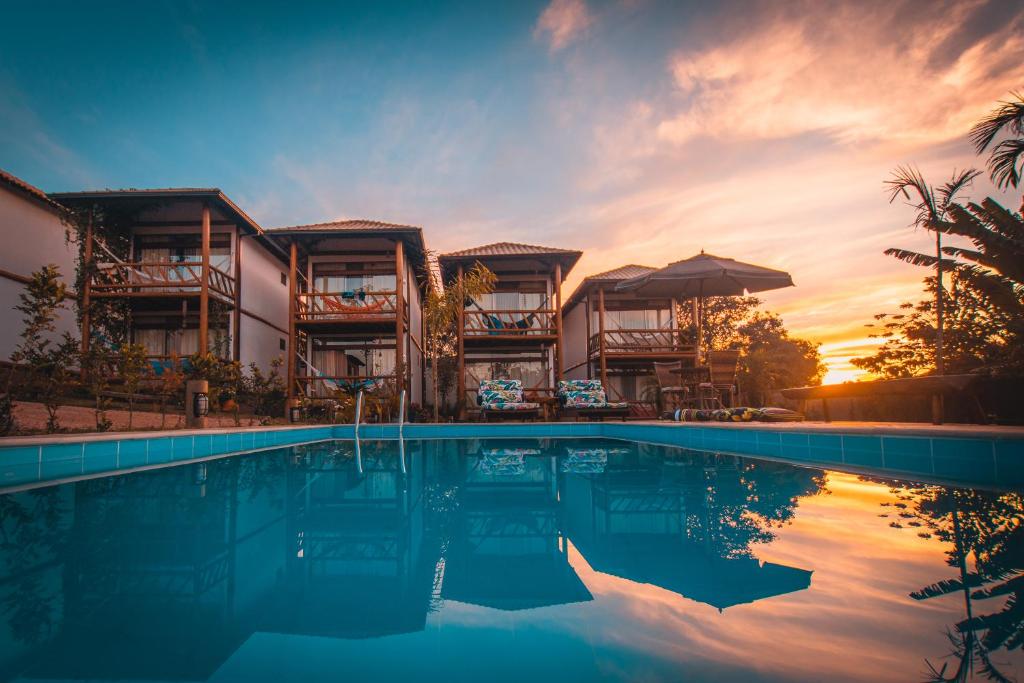 a resort swimming pool with a sunset in the background at Pousada Meu Talento in Alto Paraíso de Goiás