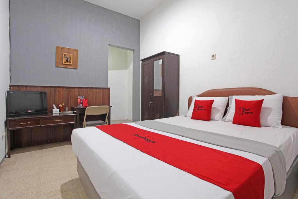 a bedroom with a large bed with red pillows and a television at RedDoorz @ Soekarno Hatta 2 in Malang