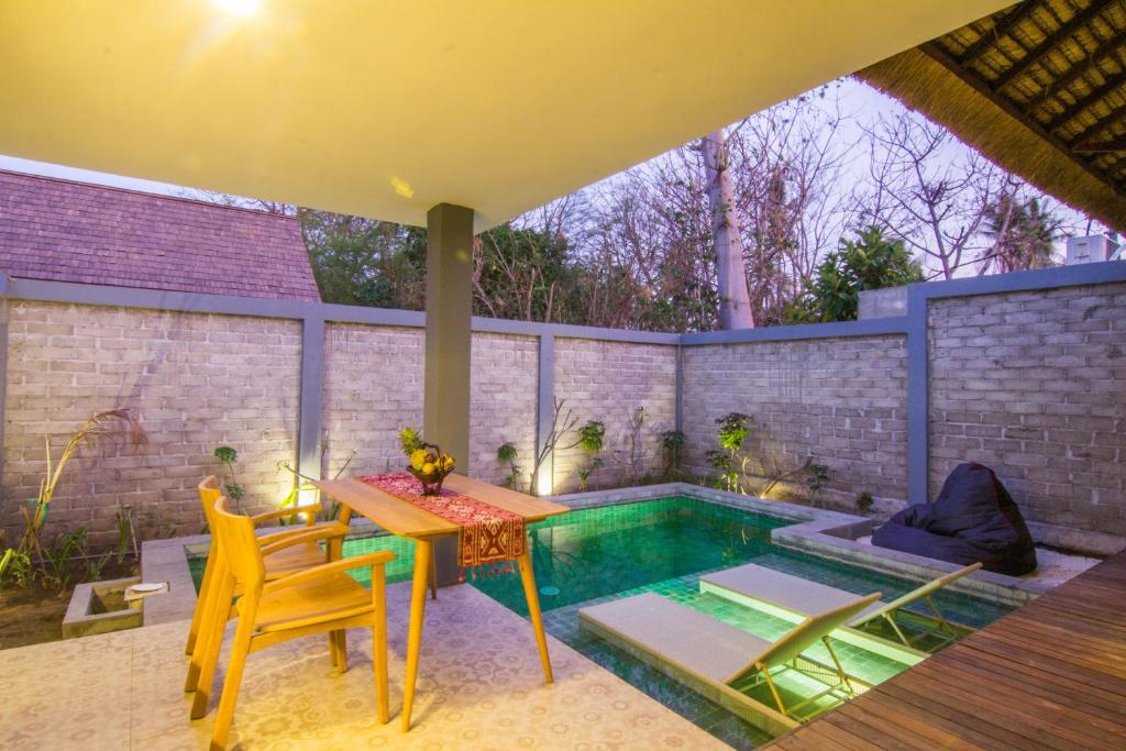 a patio with a table and chairs next to a pool at A Villa Gili Air in Gili Air