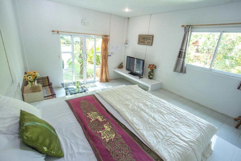 a bedroom with a large bed and a television at Greenhouse resort in Buriram
