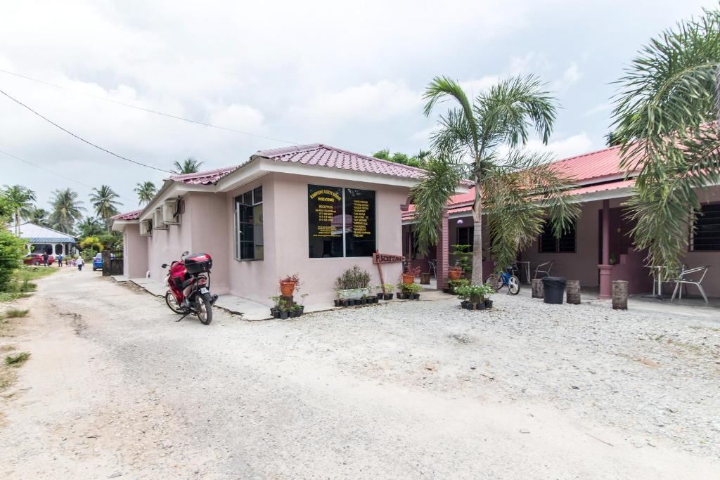 a house with a motorcycle parked in front of it at Kampung Guest House in Pantai Cenang