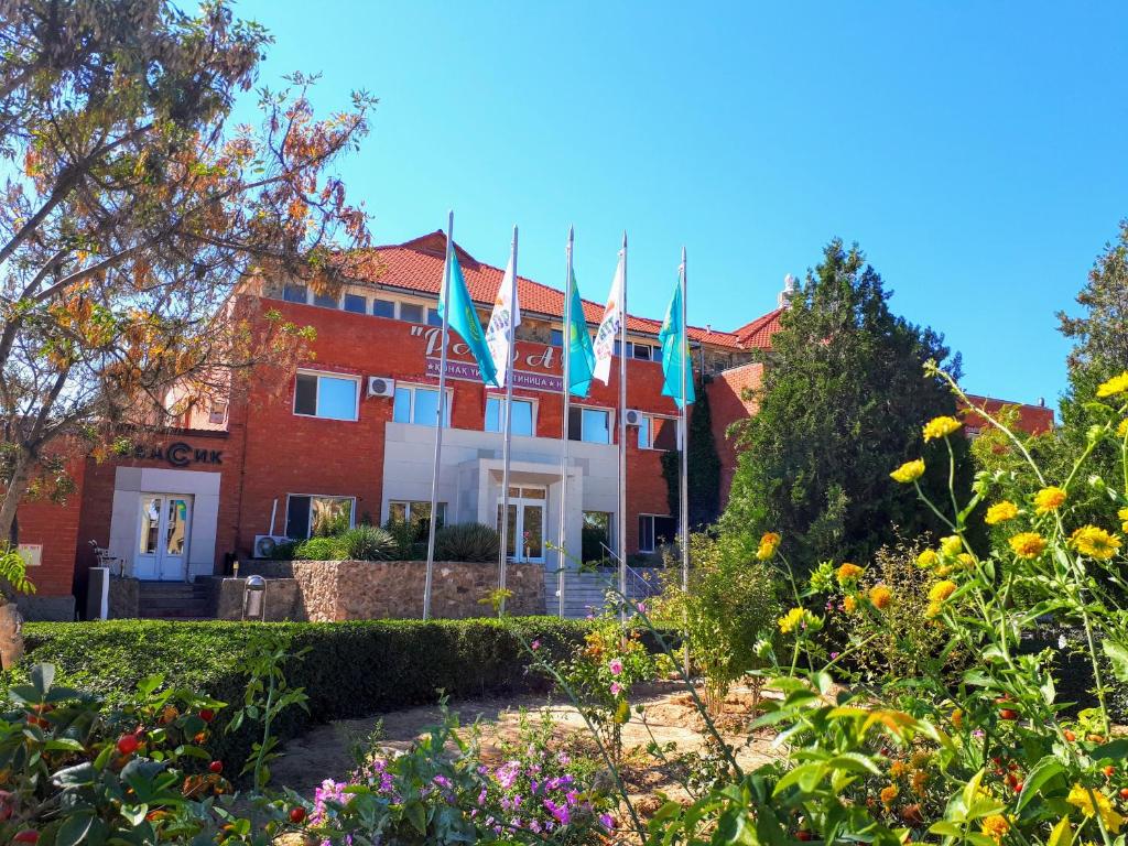 um edifício com bandeiras num jardim em Rahat Hotel em Aktau