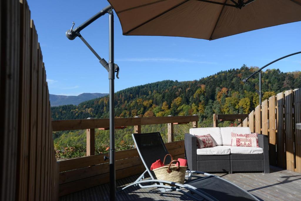 a patio with a chair and an umbrella on a deck at Hôtel Panorama in Munster