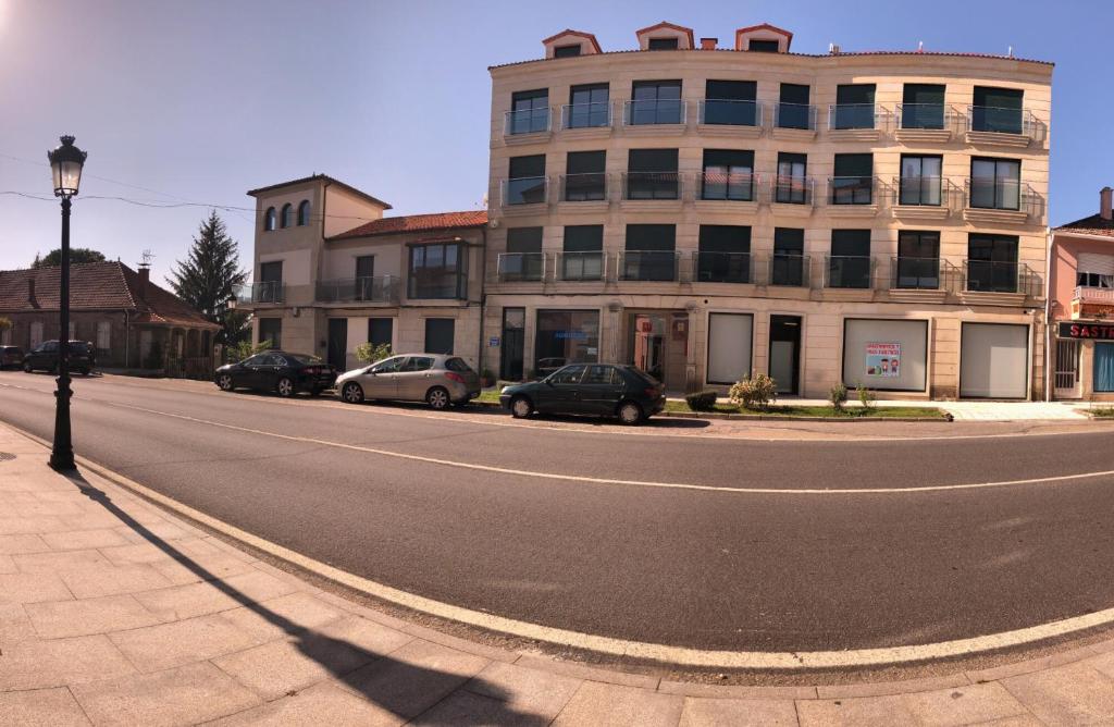 une rue vide avec des voitures garées devant un bâtiment dans l'établissement Apartamentos Augusto, à La Cañiza