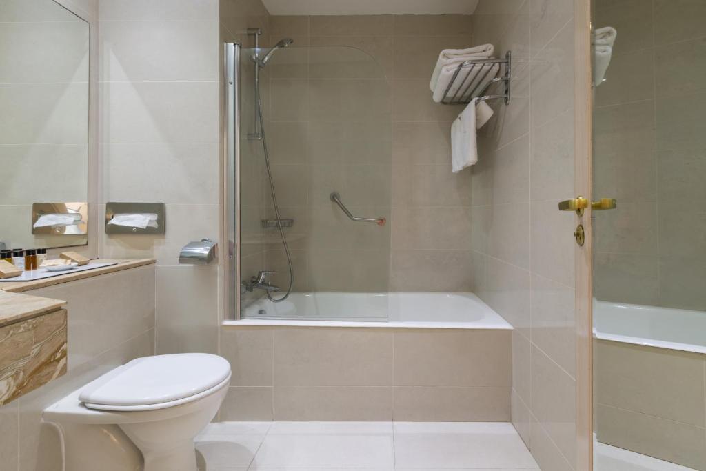 a bathroom with a tub and a toilet and a shower at Golden Bay Beach Hotel in Larnaca