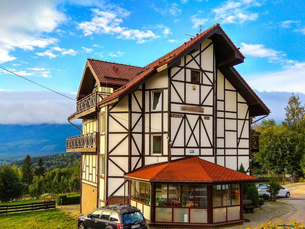 a house with a car parked in front of it at Apartament Kolorowy in Szklarska Poręba