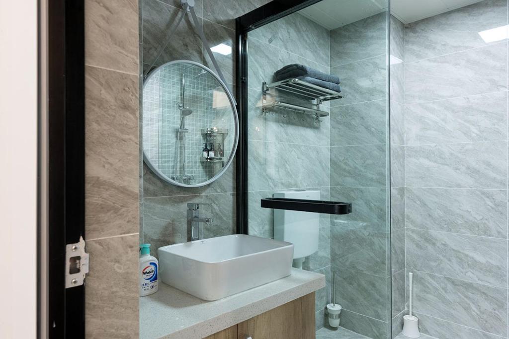 La salle de bains est pourvue d'un lavabo et d'une douche avec un miroir. dans l'établissement Chongqing Yubei·Chongqing North Railway Station· Locals Apartment 00171560, à Chongqing