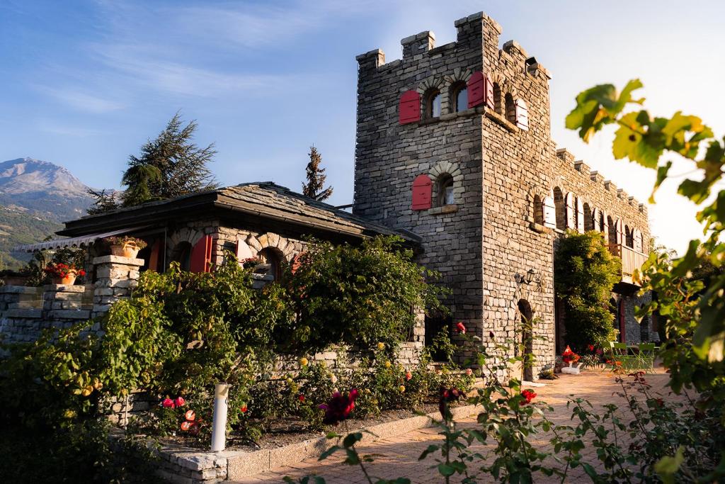 een oud stenen gebouw met rode ramen en bloemen bij Castel de Daval in Sierre