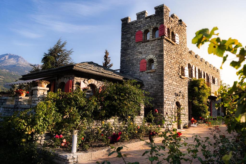 ein altes Steingebäude mit roten Fenstern und Blumen in der Unterkunft Castel de Daval in Sierre