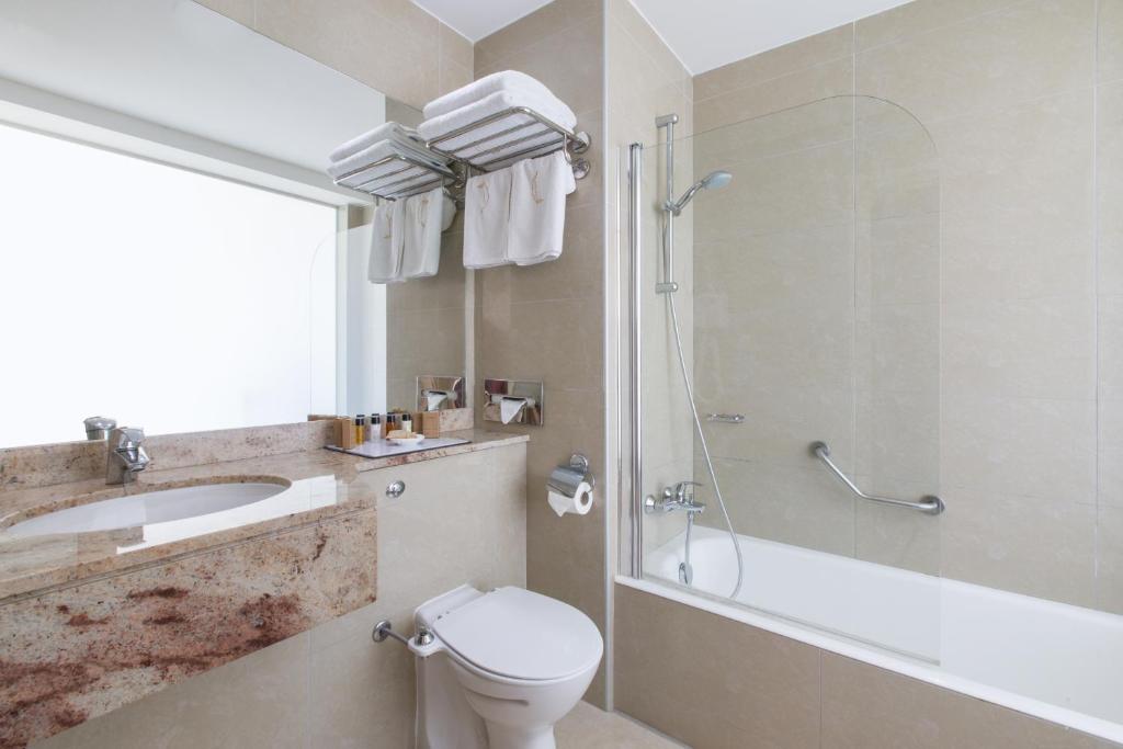 a bathroom with a toilet and a sink and a shower at Golden Bay Beach Hotel in Larnaca