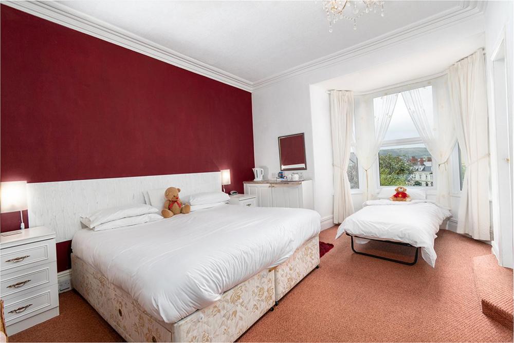 a bedroom with two beds with a teddy bear sitting on them at Anglesey House in Llandudno