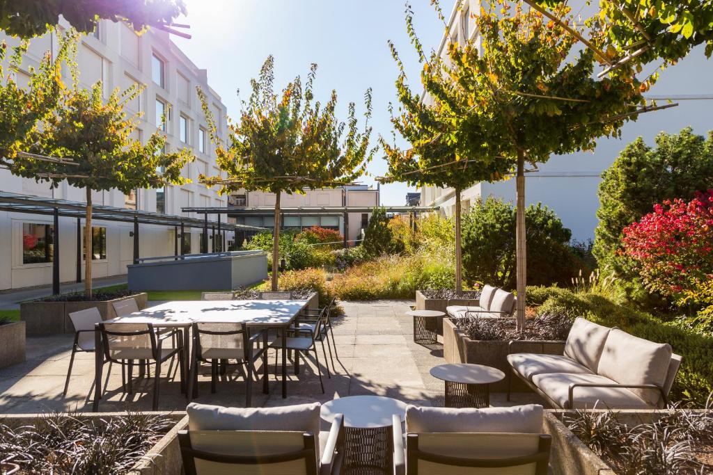 an outdoor patio with tables and chairs and trees at Pullman Basel Europe in Basel