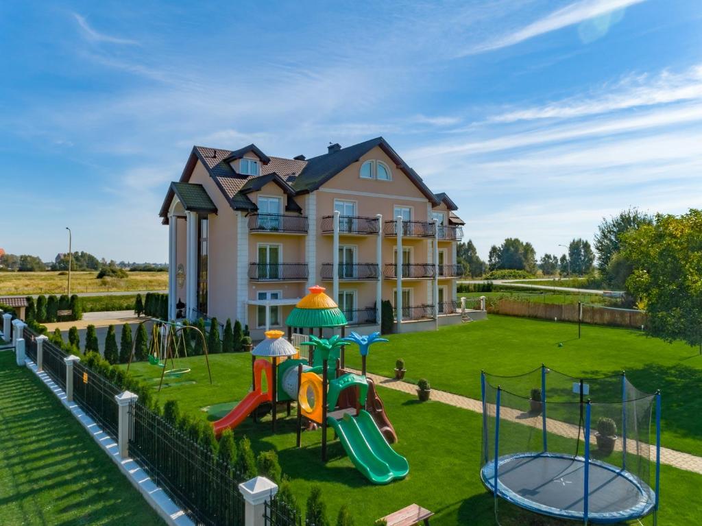 ein Haus mit einem Spielplatz davor in der Unterkunft Pensjonat Marynarski - Apartamenty in Darłówko