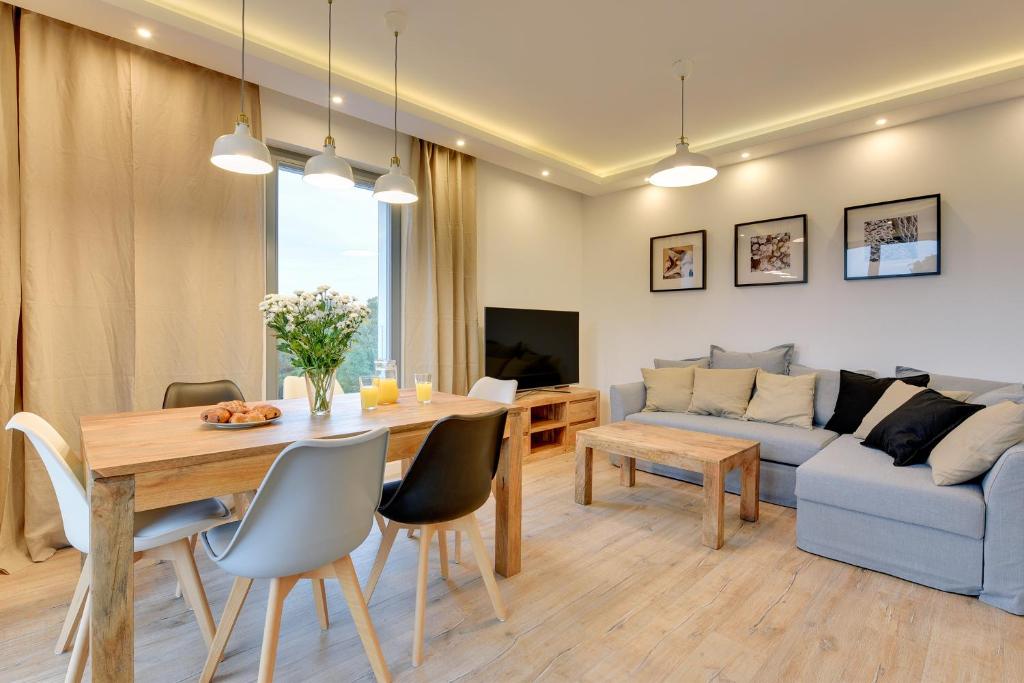 uma sala de estar com uma mesa e um sofá em The Darling Nadmorze by Baltica Apartments em Gdansk
