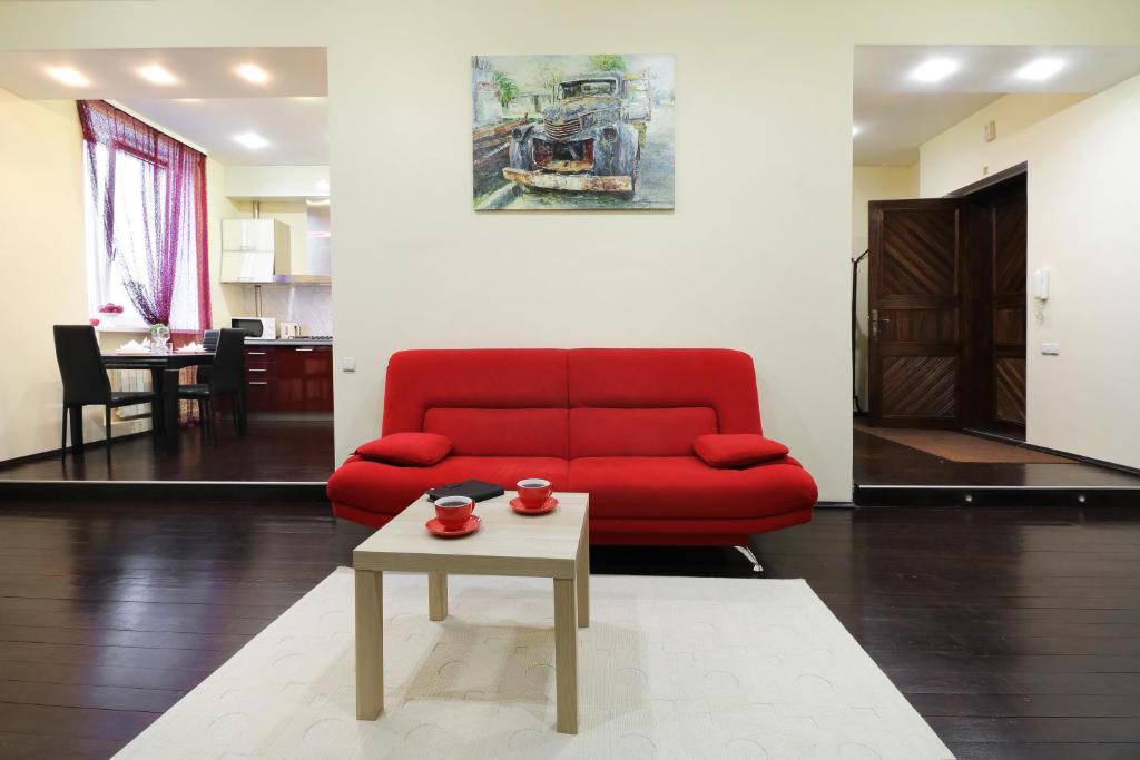 a living room with a red couch and a coffee table at PaulMarie Apartments on Lenina Avenue in Gomel