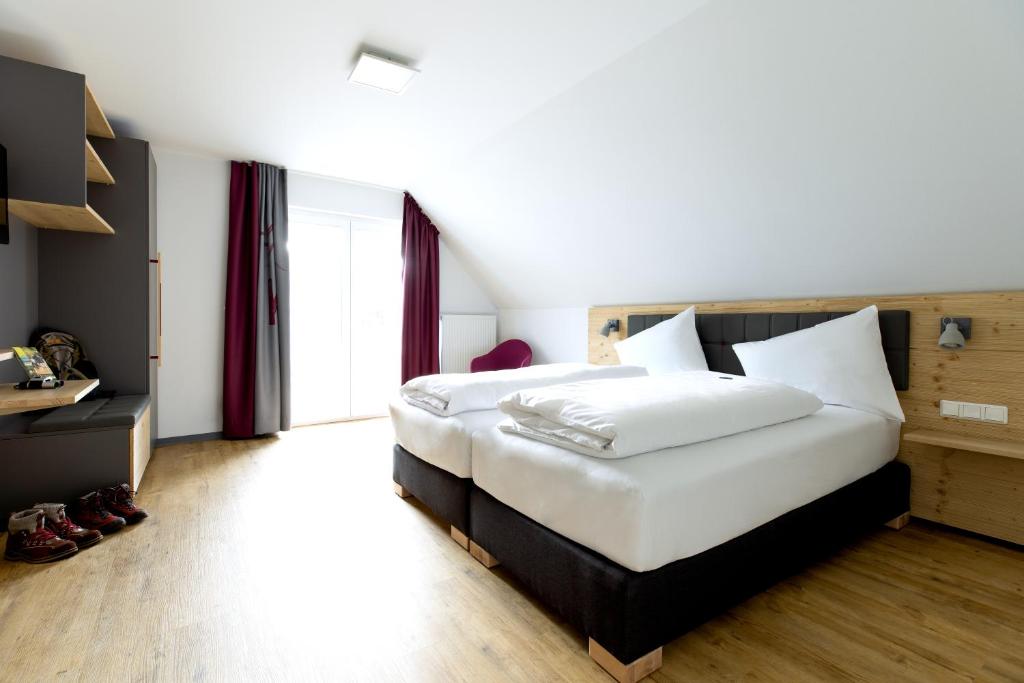 ヴィリンゲンにあるK1 Hotel Willingenのベッドルーム(白いシーツを使用した大型ベッド1台付)