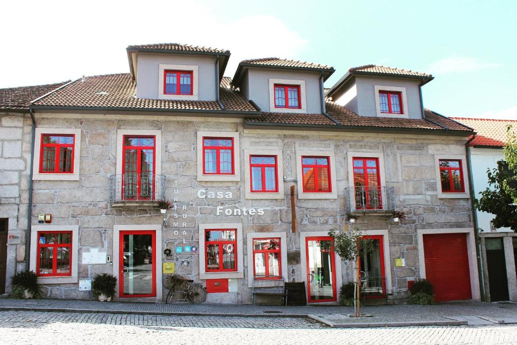 een stenen gebouw met rode deuren en ramen bij Casa Fontes in Pedras Salgadas
